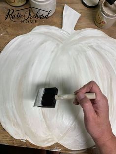 a person painting a white pumpkin on a wooden table