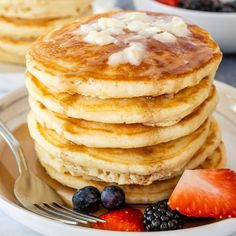 a stack of pancakes on a plate with fruit