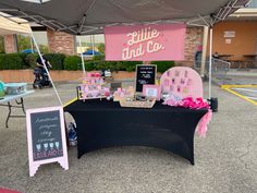 a black table topped with pink and white items next to a sign that says hello kitty