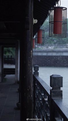 a bird cage hanging from the side of a building next to a body of water