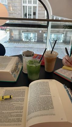 an open book sitting on top of a table next to a cup of green tea