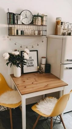 a kitchen table with two chairs next to it and a white refrigerator in the background