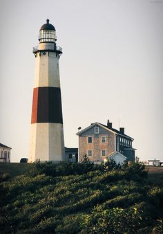 a light house sitting on top of a hill next to a building with a black and white roof