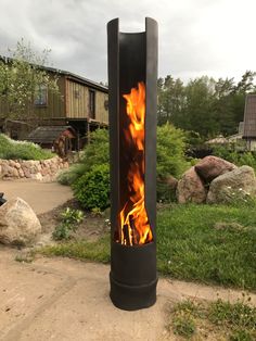 a fire pit sitting in the middle of a yard next to some rocks and grass