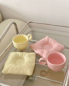 a glass table topped with two cups and a tray filled with dishes on top of it