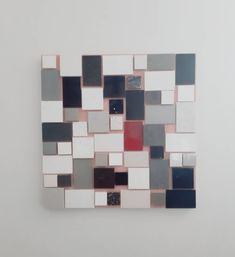 an abstract piece of art made out of various colored squares and rectangles on a white wall