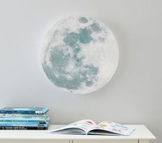 a book is sitting on a table next to a full moon wall decal,