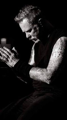 a black and white photo of a man with tattoos on his arm holding a candle