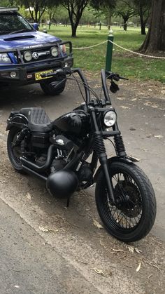 a motorcycle parked on the side of a road next to a blue pick up truck