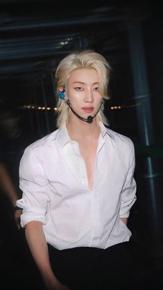 a woman with blonde hair wearing a white shirt and black pants is looking at the camera