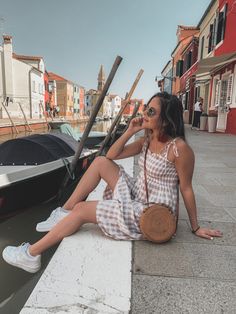 a woman sitting on the edge of a pier next to boats