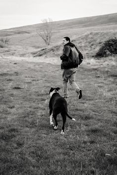 a man and his dog are running in the field together, one is carrying a backpack