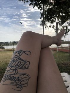 a woman's legs with tattoos on them sitting on a bench in the park