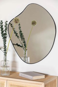 a mirror on the wall above a vase with flowers