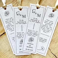 three wedding program bookmarks hanging on a tree stump with ribbon and tags attached to them