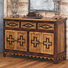 a wooden sideboard with decorative carvings on the doors and drawers in front of a mirror