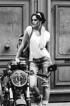 a woman standing next to a parked motorcycle