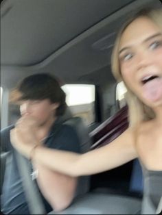 two people sitting in the back seat of a car with their mouths open and one woman sticking her tongue out