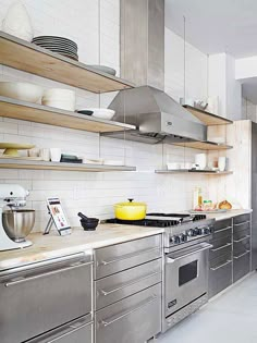 a kitchen with stainless steel appliances and wooden shelves