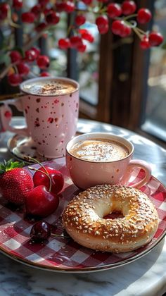 two cups of cappuccino and bagel on a table with cherries