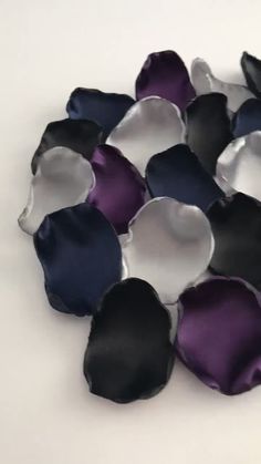 purple and black flower petals laying on top of each other in the middle of a white surface