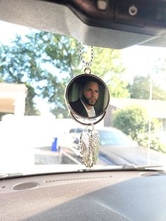 a car dashboard with a necklace hanging from it's front window and a man in the background