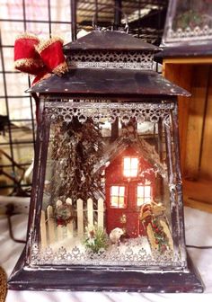 a lantern with a red house on it sitting on a table next to other items