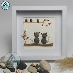 two cats sitting on a branch with leaves and rocks