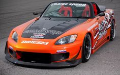 an orange sports car driving down a race track