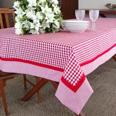 a red and white checkered table cloth on a dining room table with flowers in the center