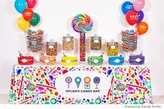 an assortment of candy and candies displayed on a table with balloons in the background