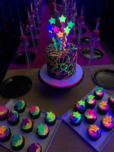 a table topped with lots of cupcakes covered in neon colored frosting and stars