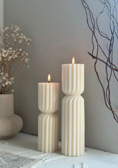 two white candles sitting next to each other on a table