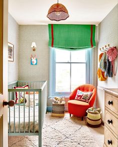 a baby's room with a crib, chair and window