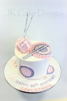 a birthday cake decorated with crochet and knitting needles on top of a plate