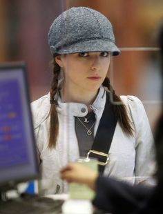 a woman wearing a hat is looking at her computer