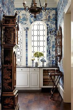 a kitchen with blue and white wallpaper, windows, cabinets and a sink in it