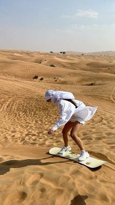 a person riding a snowboard on top of a sandy surface in the desert,