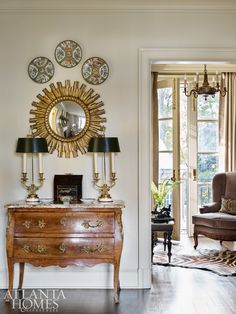 a living room filled with furniture and a large mirror on the wall over a wooden dresser