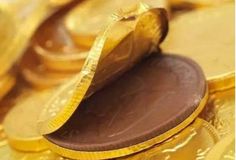 a pile of gold coins with a chocolate piece in the middle and a golden wrapper on top