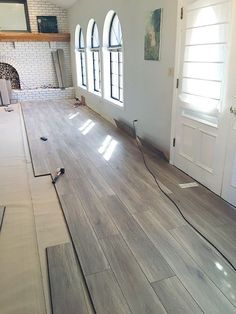 an empty room with hard wood flooring in the foreground and windows on the far wall