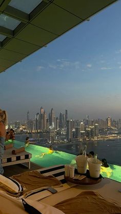 a woman sitting at a table on top of a roof overlooking a cityscape