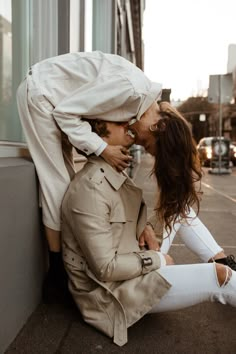 a man and woman kissing while sitting on the ground