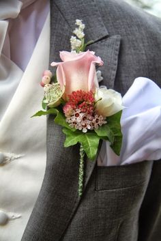 a boutonniere with pink flowers and greenery is worn on a man's suit