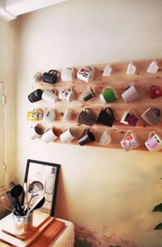 there are many cups on the wall with magnets attached to it and pictures hanging up against the wall