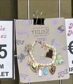 two price tags hang on a rack with bracelets and charms in front of them