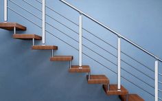 a set of stairs with wooden treads and handrails against a blue wall