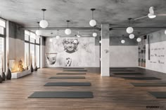 an empty gym with yoga mats on the floor and large windows to the side,