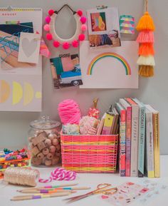 there are many crafting supplies on the table and in front of it is a basket with pom - poms