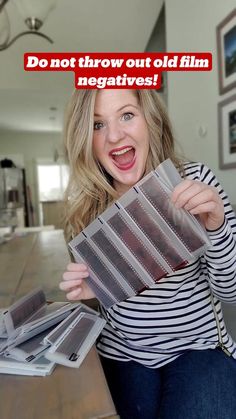 a woman sitting on the floor holding up several film negatives in front of her face